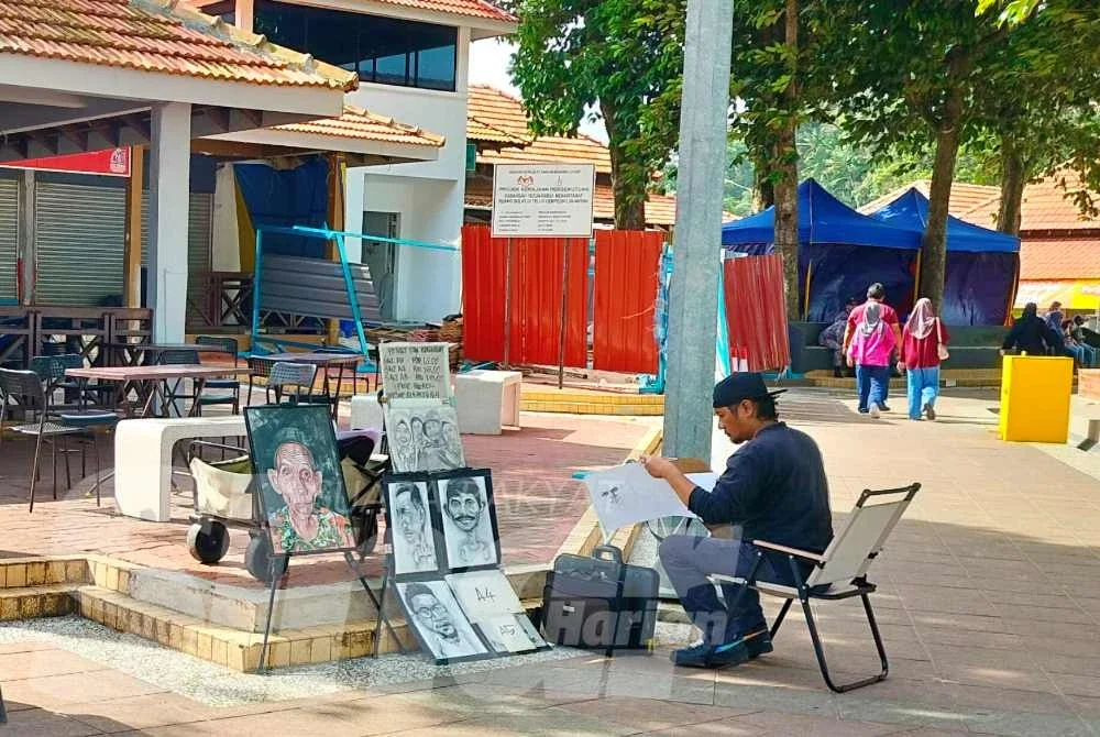 Seorang pelukis di Pantai Teluk Cempedak tekun menyiapkan lukisan potret yang ditempah pengunjung.