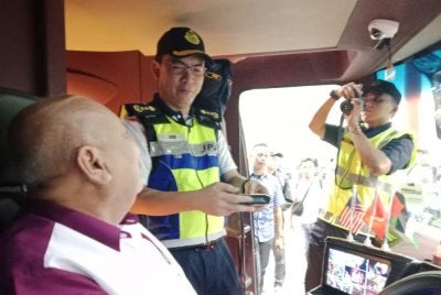 Azrin (tengah) beramah mesra dengan seorang pemandu bas ketika meninjau pelaksanaan Operasi Khas Tahun Baharu Cina di Terminal Seksyen 17, Shah Alam pada Jumaat.