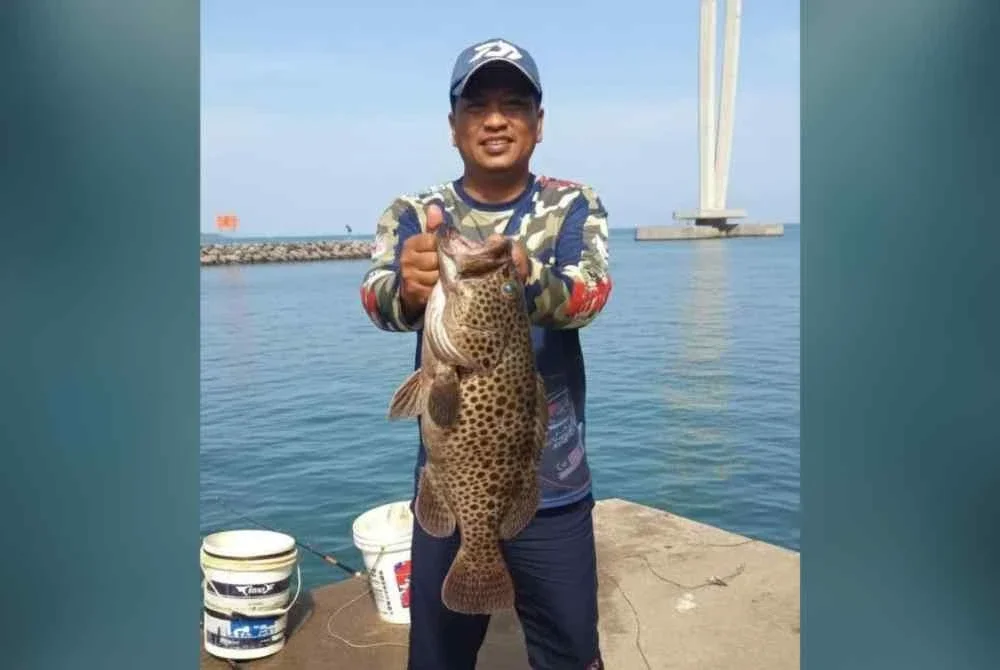 Saiful Azhar menunjukkan ikan yang berjaya dinaikkan hasil memancing di bawah Jambatan Pulau Pinang.