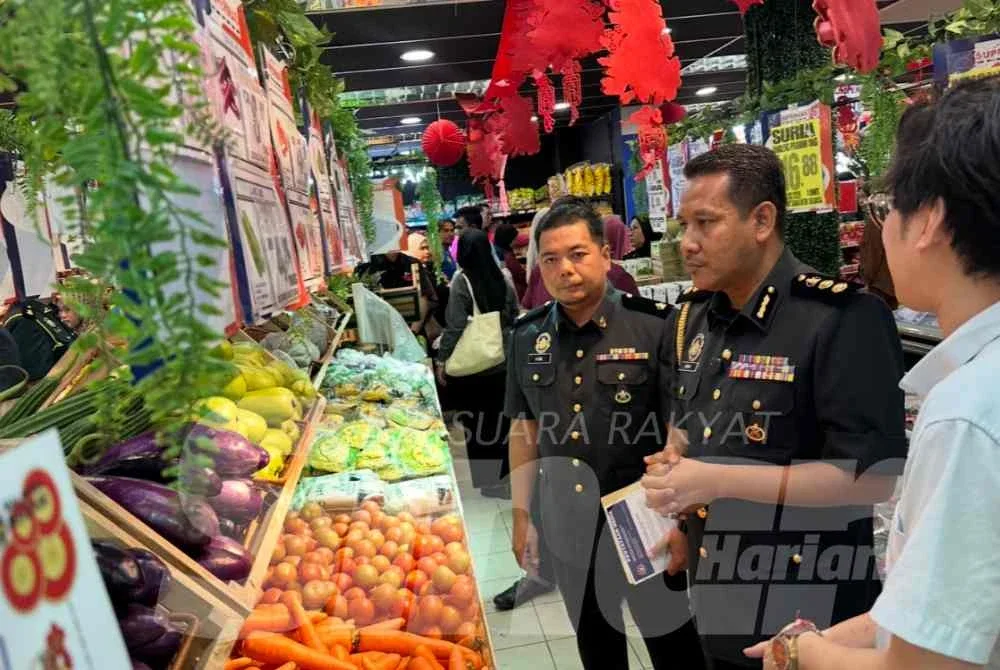 Aswadi (tengah) memantau harga sayur-sayuran yang dijual di pasar raya berkenaan. 