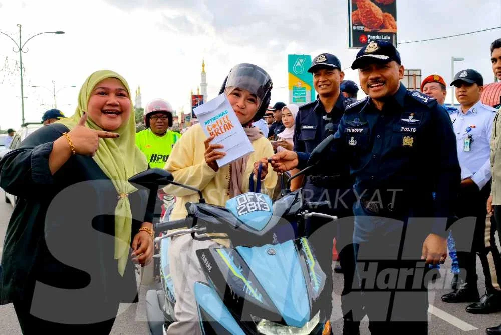 Mohd Yusoff (kanan) menyantuni pengguna jalan raya semasa merasmikan Kempen Kesedaran dan Keselamatan Jalan Raya Sempena Op Selamat 25 Tahun Baharu Cina di Pasir Pekan, Tumpat pada Ahad.Foto:SINAR HARIAN/HAZELEN LIANA KAMARUDIN