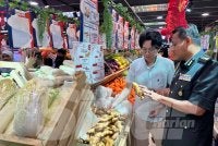 Aswadi (kanan) dan Chin Huei (kiri) melihat halia yang dijual di pasar raya berkenaan. 