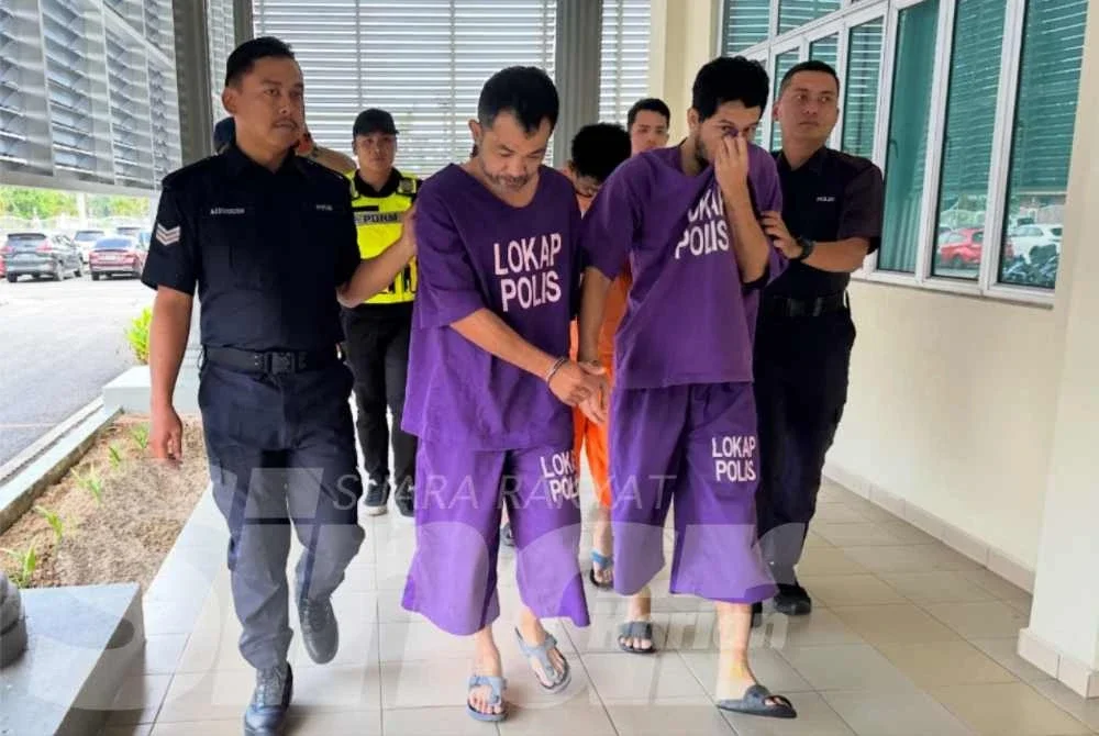 Mohd Fairul Mu’min (dua dari kiri) dan Mohd Azman (dua dari kanan) berjalan menuju ke lokap mahkamah. 