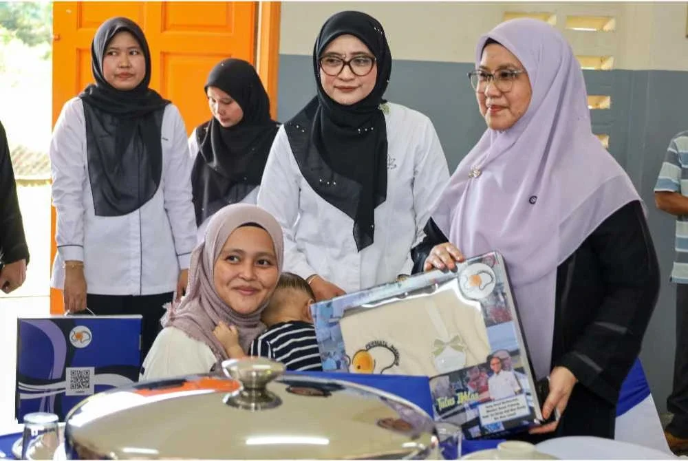 Salah seorang penerima tersenyum menerima manfaat daripada Kerajaan Negeri yang disampaikan Sabariah selepas Majlis Pelancaran Permata Makmur Tahun 2026 di Dewan Serbaguna Felda Kampung Sertik. - Foto: Pahang Media
