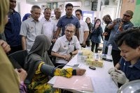 Fahmi (tengah) diiringi Abdul Halim (dua dari kiri) beramah mesra dengan penduduk ketika mengadakan lawatan pada Hari Bersama Komuniti di Pusat Sebaran Maklumat Nasional (NADI) Taman Desa Belantik di Projek Perumahan Rakyat Sri Stulang pada Isnin. Foto Bernama