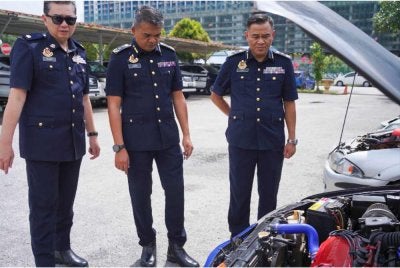Hamidi (tengah) melihat kenderaan yang disita.