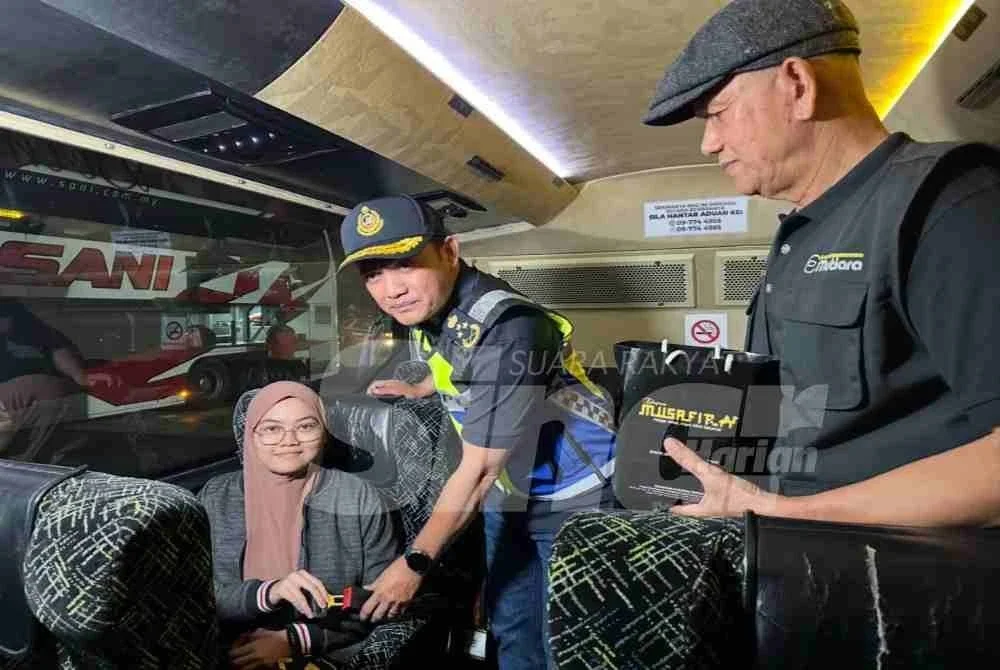Jazmanie (tengah) memeriksa tali pinggang keledar penumpang bas.

