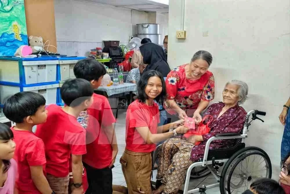 Niau Ying membantu ibunya, Hui Lang memberikan angpau kepada cucu dan cicit pada sambutan Tahun Baharu Cina di rumahnya di Indera Mahkota, pada Selasa.