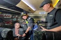 Jazmanie (tengah) memeriksa tali pinggang keledar penumpang bas.
