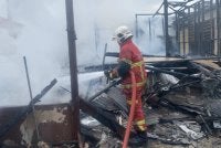 Seorang anggota bomba sedang memadamkan kebakaran di Kampung Melayu Ampang, Ampang pada Selasa.