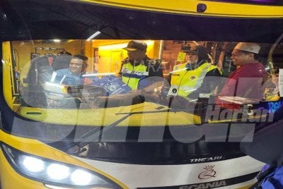 Jazmanie (dua dari kanan) melakukan pemeriksaan terhadap pemandu bas ekspres. 
