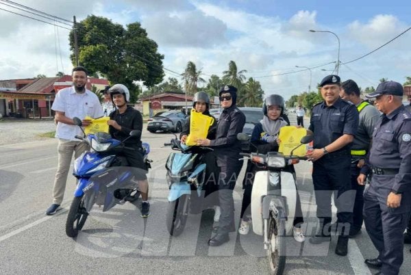 Mohamad Ismail (dua dari kanan) menyerahkan cenderahati kepada penunggang motosikal. 