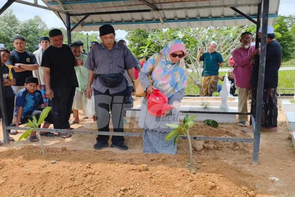 Sawidah dan suami, Abdul Wahab Yazid, 66, menjirus air di pusara anak bongsunya yang selamat dikebumikan kira-kira jam 2 petang di Tanah Perkuburan Islam Mukim Sri Gedombak, Pasir Puteh pada Khamis. Foto:SINAR HARIAN - HAZELEN LIANA KAMARUDIN