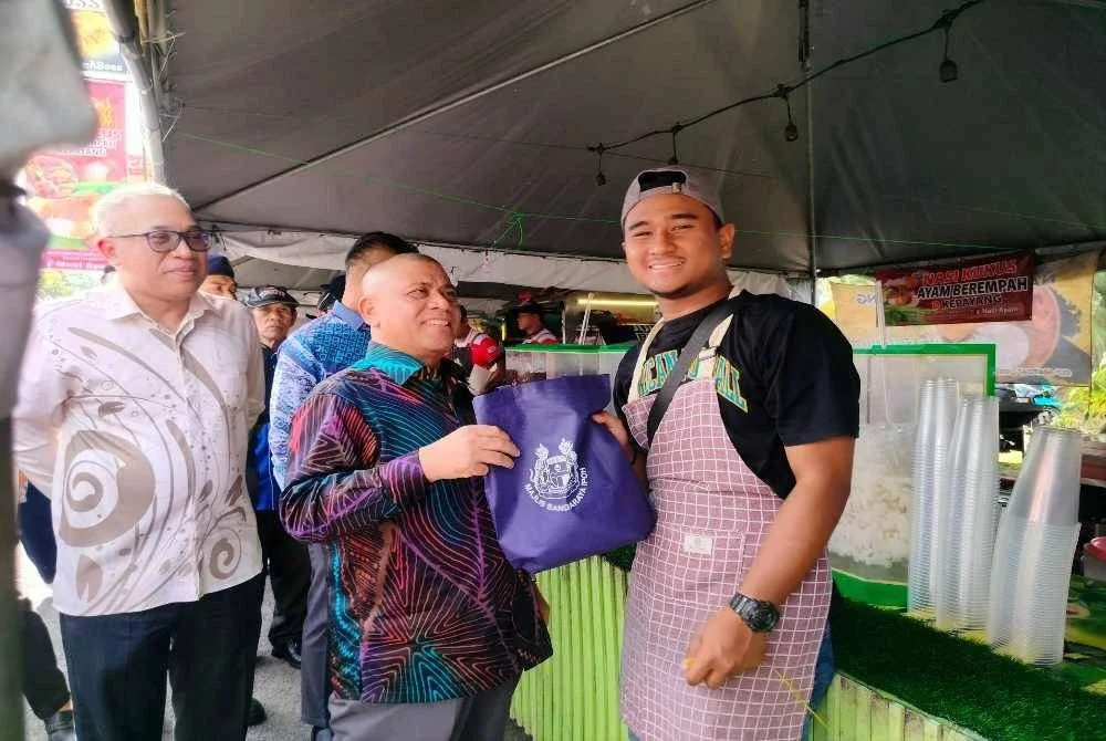 Saarani (tengah) menyampaikan apron kepada peniaga ketika mengadakan lawatan mesra ke Bazar Ramadan Pekarangan Stadium Perak di sini pada Khamis.