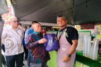 Saarani (tengah) menyampaikan apron kepada peniaga ketika mengadakan lawatan mesra ke Bazar Ramadan Pekarangan Stadium Perak di sini pada Khamis. 