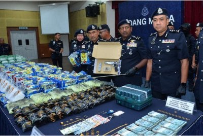 Hussein (dua dari kanan) menunjukkan pistol yang dirampas susulan tangkapan tiga individu melibatkan sindiket dadah di Sekinchan, Sabak Bernam. 