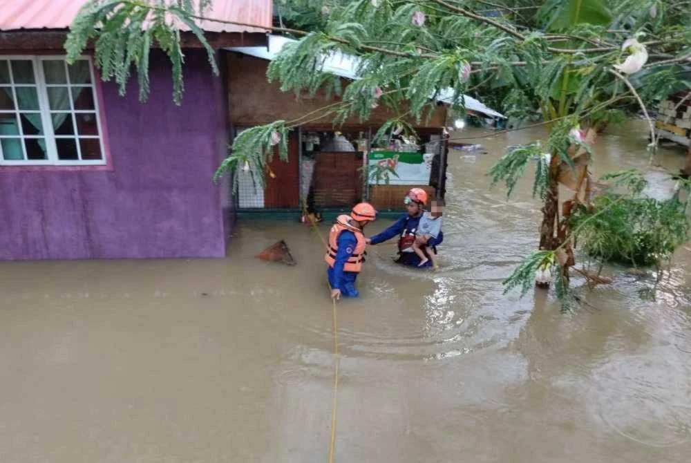 Anggota APM Sandakan membantu penduduk yang terjejas banjir. Foto APM Sandakan