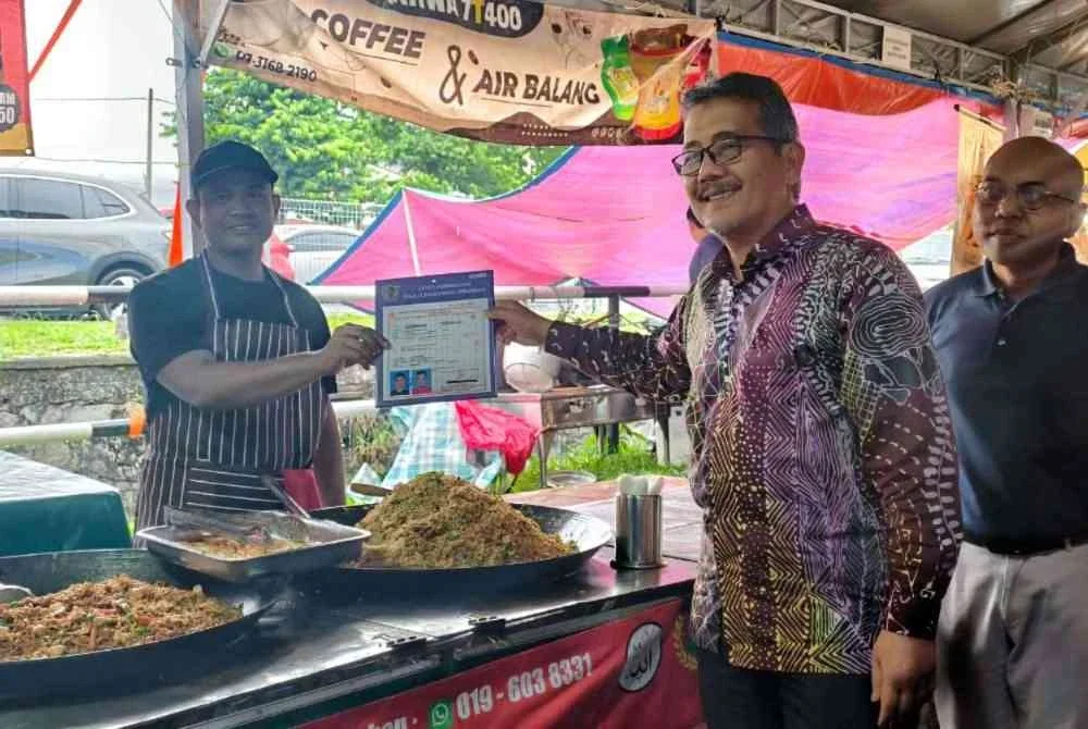 Masri menyerahkan lesen kepada peniaga di Bazar Ramadan Ampangan.