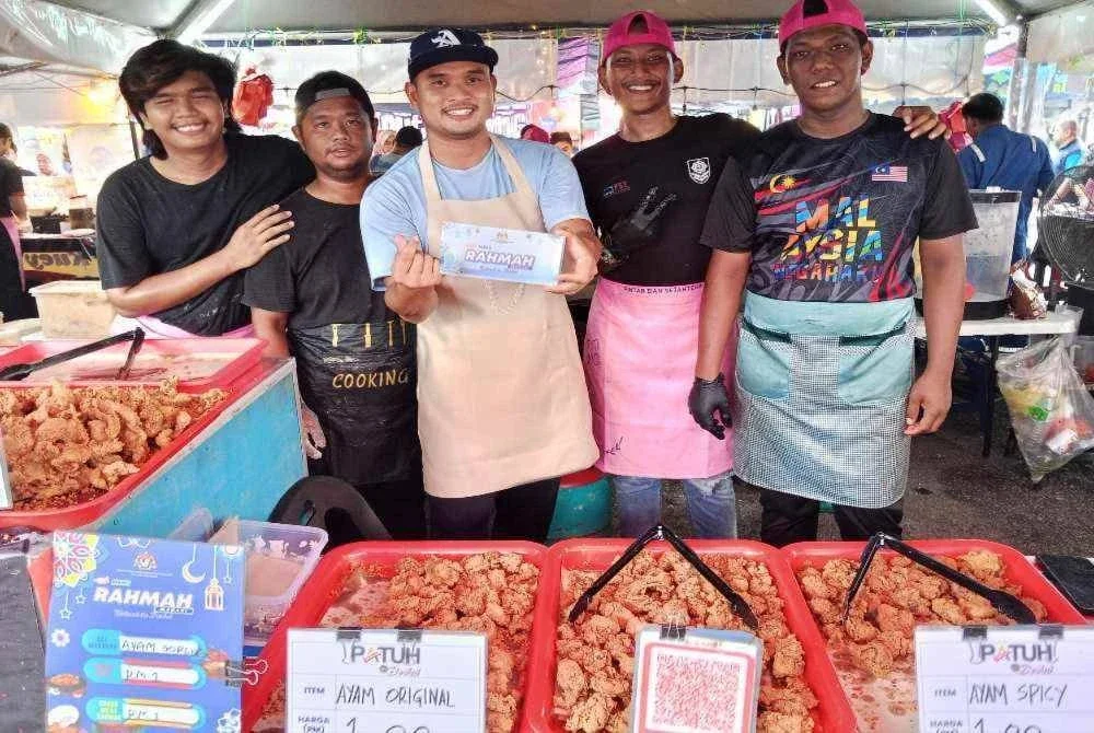 Abdul Halim ( dari kanan) menyediakan juadah ayam goreng pada harga RM 1 di Bazar Rahmah Ramadan Perling.