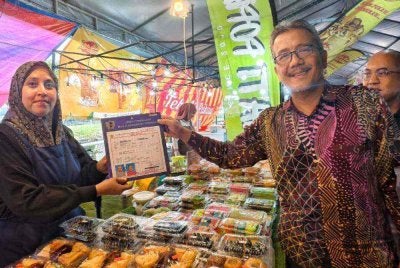 Masri menyerahkan lesen kepada peniaga di Bazar Ramadan Ampangan.