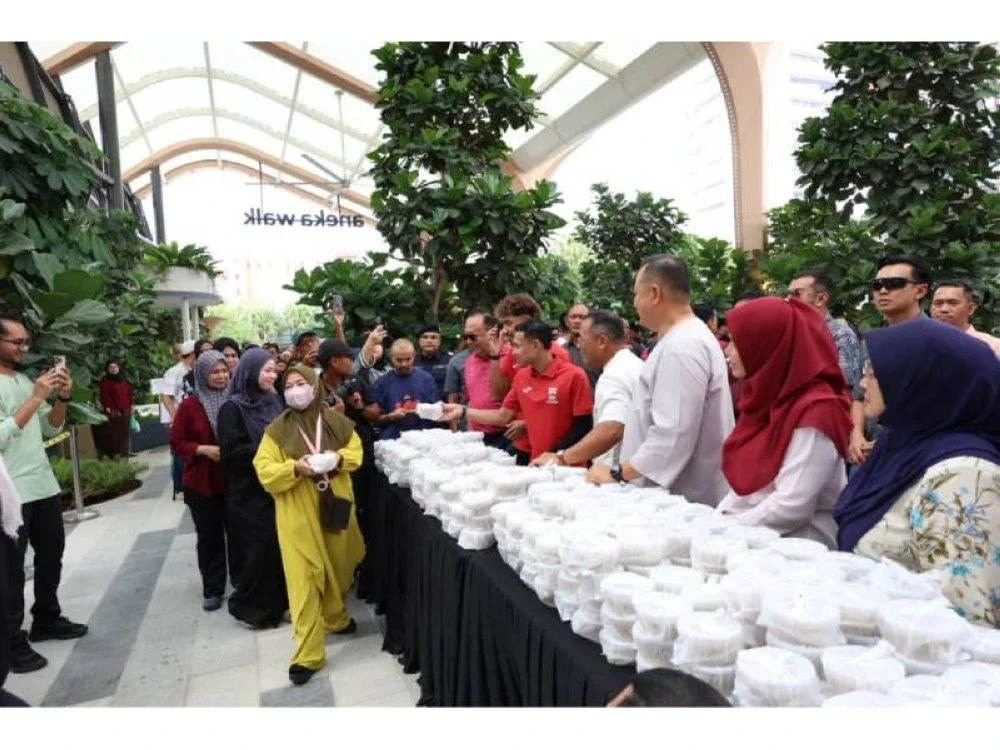 Amirudin (tiga, kanan) bersama pemain Selangor FC mengedarkan bubur lambuk PKNS kepada orang ramai di di Aneka Walk di sini pada Jumaat.