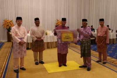 Sultan Kedah (tengah) berkenan secara simbolik menyampaikan kotak kurniaan berupa barangan makanan kepada penerima yang telah dikenal pasti kepada Pegawai Daerah.