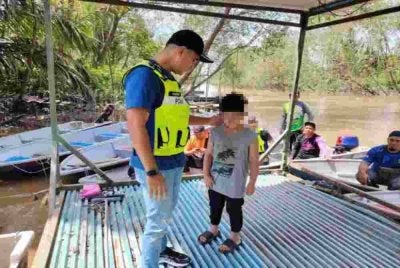 Hadzrat Hussien bersama kanak-kanak malang itu ketika operasi mencari dan menyelamat bapanya yang dikhuatiri lemas di Sungai Parit Bugis, Pontian.