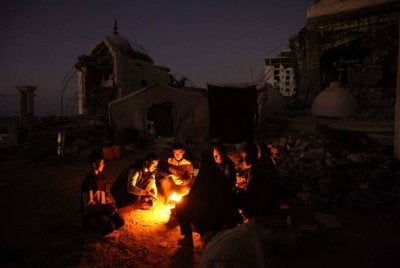 Keluarga al-Ghafir yang dipindahkan berbuka puasa di sisi khemah mereka yang didirikan di celah runtuhan Masjid al-Hasayna, Gaza City. - AFP