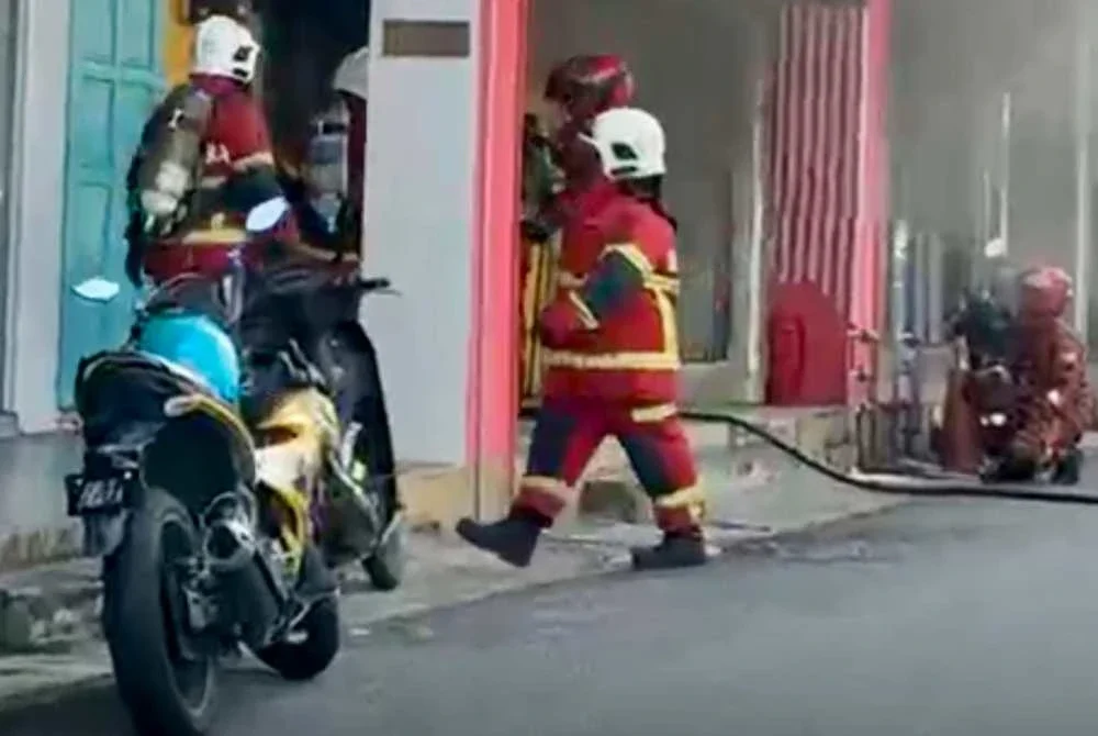 Anggota bomba berusaha memadamkan senbuah kedai minuman yang terbakar di Taman Kenangan, Kota Bharu pada Selasa.