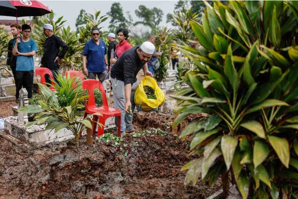 Mohd Izani menaburkan bunga mawar di pusara ibunya, Datin Fatimah yang juga bekas ADUN Banting di Masjid Jamiatul Islamiah Batu 9, Kampung Medan, pada Rabu. Foto Bernama