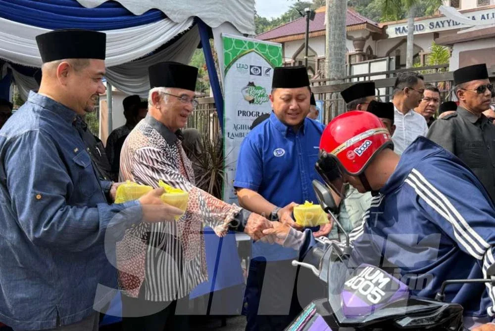 Tun Mohd Ali (dua dari kiri) mengedarkan bubur lambuk sempena kedatangan Ramadan di Masjid Sayyidina Ali pada Selasa.