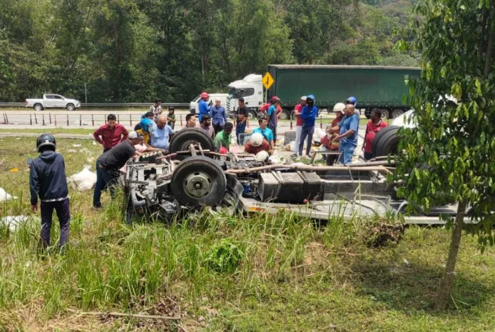 Orang ramai cuba membantu pemandu lori dan kelindan yang terlibat dalam kemalangan di Persiaran Mokhtar Dahari pada Rabu. 