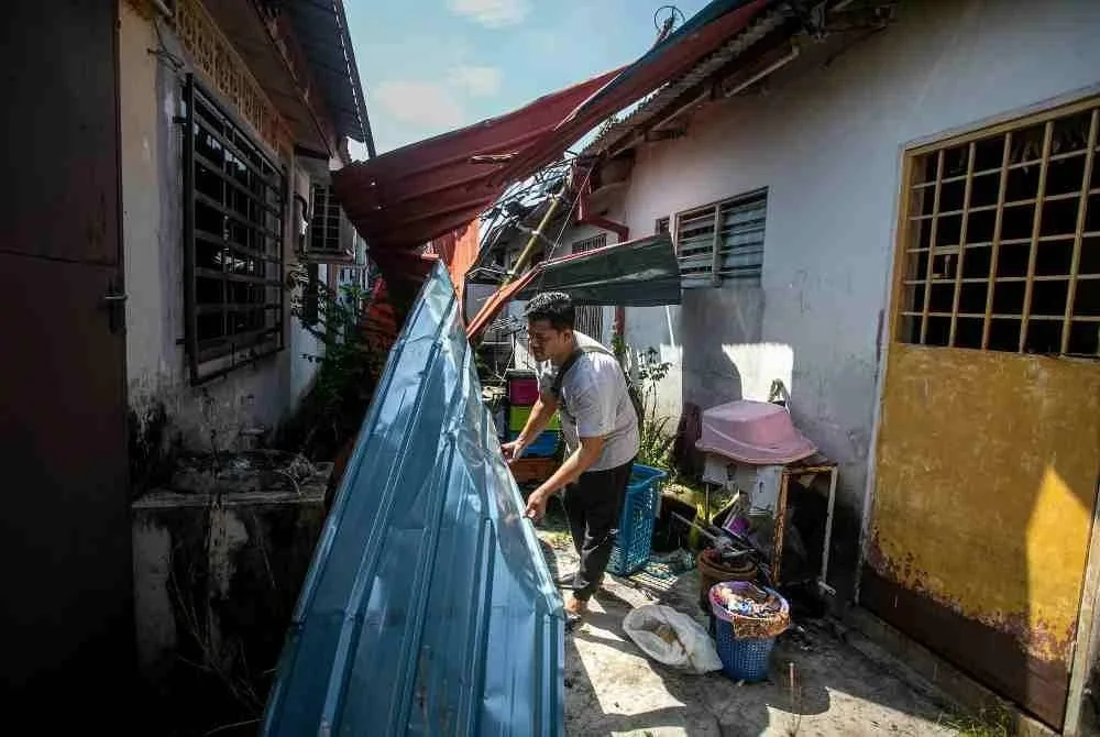 Muhammad Qhushairi mengalihkan sengkuap yang rosak susulan kejadian ribut ketika tinjauan Bernama di Taman Ria, pada Rabu. Foto Bernama