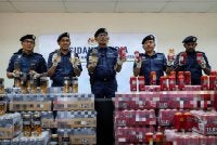 Rohaizad (tengah) menunjukkan minuman keras yang dirampas di Pangkalan Kontena Butterworth Utara pada 7 Januari lepas ketika mengadakan sidang media di Stor Penguatkuasaan Bagan Jermal pada Rabu. Foto Bernama