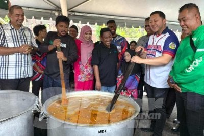 Mohd Ridhwan (dua dari kanan) mengacau bubur lambuk pada Program Agihan Bubur Lambuk di Masjid Sayyidina Ali pada Selasa