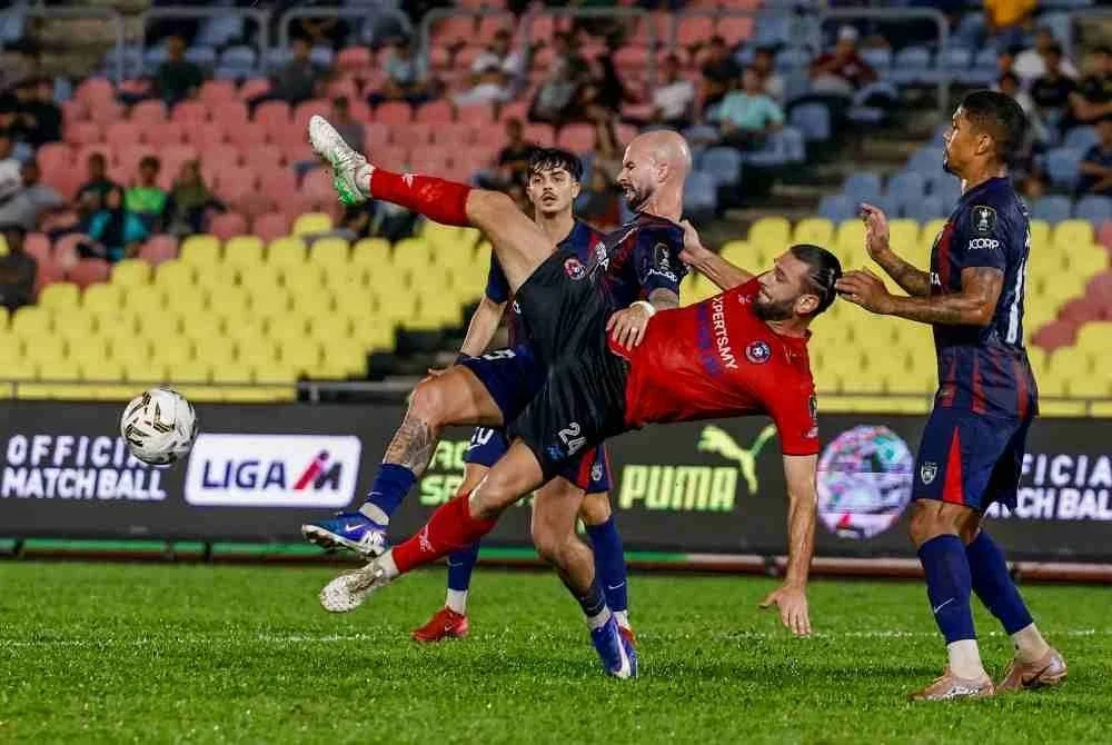Pemain Melaka FC Argzim Redzonic (jersi merah) cuba mengasak pemain-pemain JDT FC pada perlawanan Bola Sepak suku akhir kedua Piala Malaysia di Stadium Hang Jebat, Krubong, pada Rabu. Foto Bernama