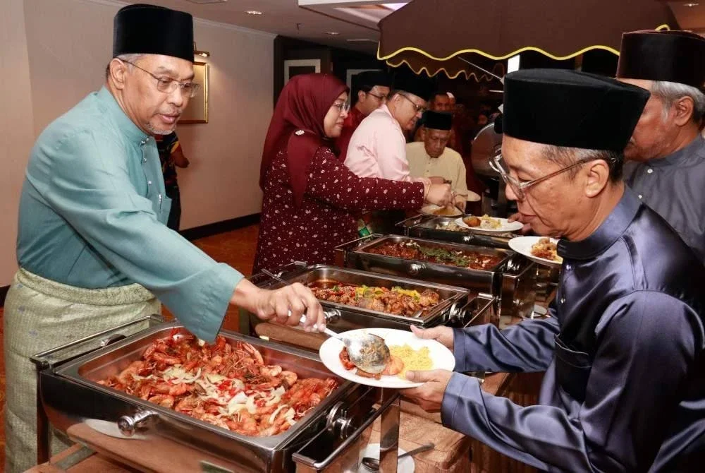 MOHAMED RAFIK (kiri) membantu menyenduk lauk buat tetamu yang diraikan dalam Majlis Nur Kasih Ramadan. 