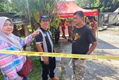 Norizan dan suaminya, Azahari (kanan) dan salah seorang abangnya menunjukkan keadaan rumah peninggalan arwah ibunya yang musnah terbakar hingga meragut nyawa penyewa yang terdiri daripada lima sekeluarga.