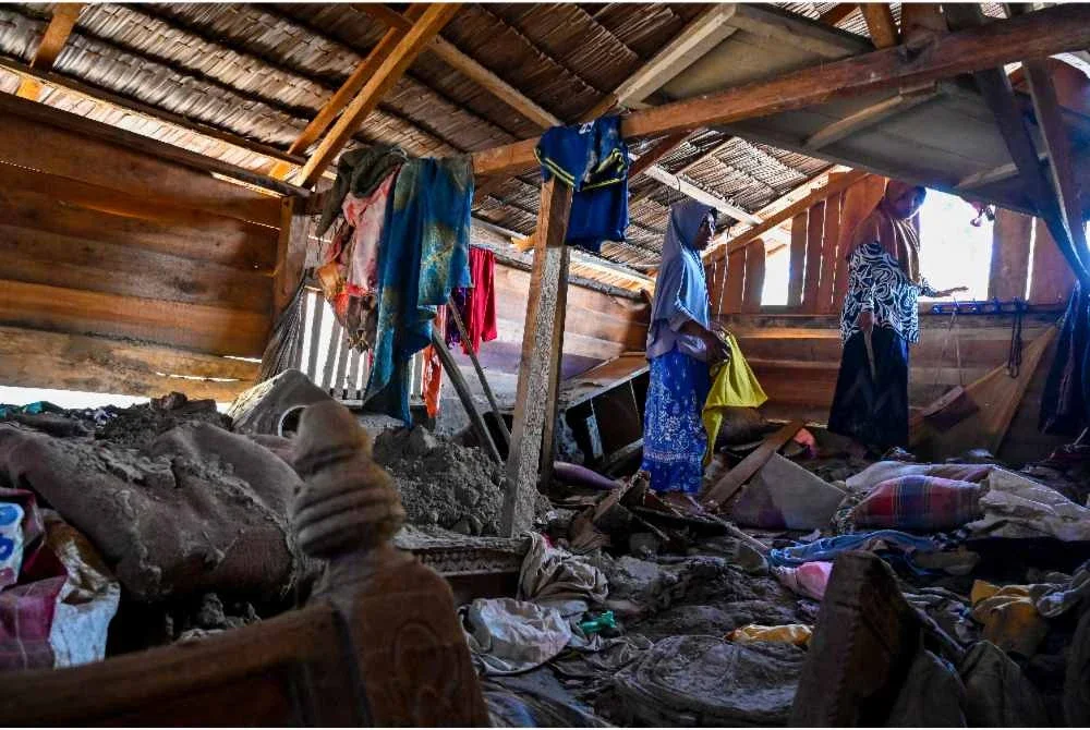 Mangsa banjir, Rauzah (kiri), ibu kepada empat anak, menyelamatkan barangan dari rumahnya yang rosak di Meurah Dua, daerah Pidie Jaya, wilayah Aceh.-AFP