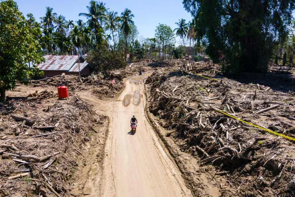 Seorang penunggang motosikal melalui kawasan perumahan yang rosak akibat banjir kilat di Meurah Dua, daerah Pidie Jaya, wilayah Aceh, selepas banjir dan tanah runtuh melanda Sumatera hujung tahun lalu.-AFP