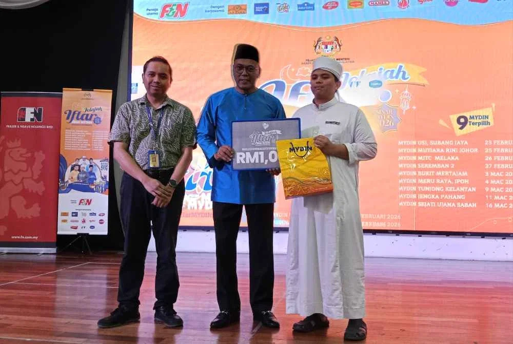 Pandak (tengah) menyerahkan sumbangan baju raya kepada pelajar Madrasah al-Quran Sinaran Baru.