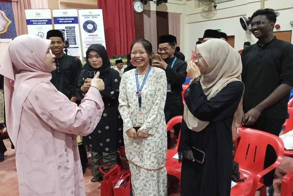 Fadhlina (kiri) bertanya khabar pelajar yang hadir pada Program Jaulah Rama di SMKA Maahad, Muar.