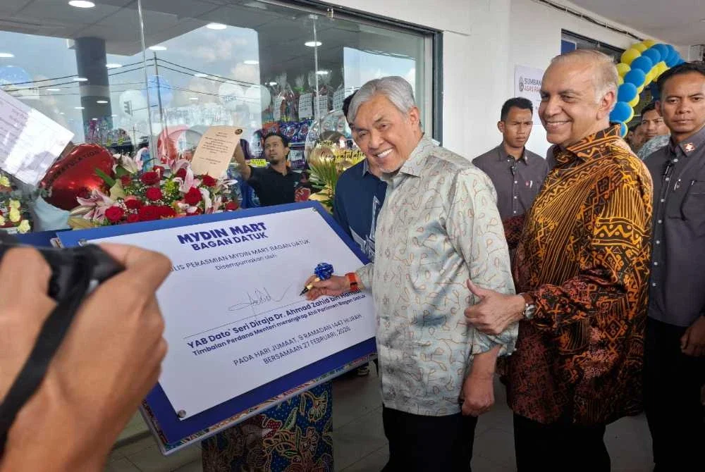 Ahmad Zahid menandatangani plak perasmian Mydin Mart Bagan Datuk sempena pembukaan pada Jumaat. Turut kelihatan, Pengarah Urusan Mydin, Datuk Ameer Ali Mydin.