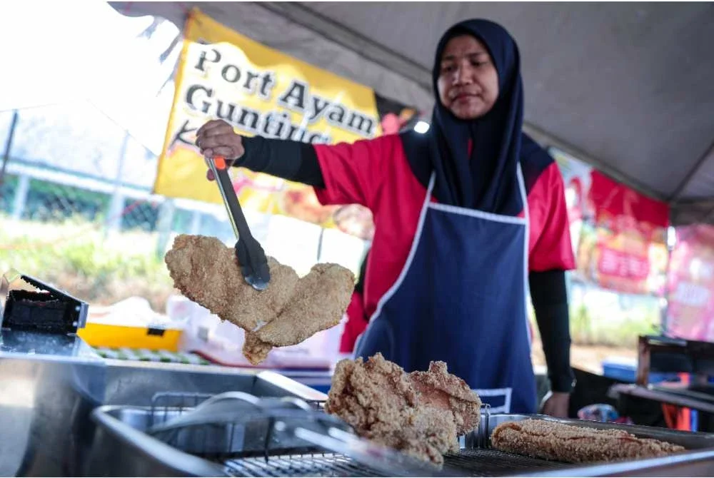 Aziani menyiapkan juadah ayam gunting yang dijual pada harga Rahmah di Bazar Ramadan Rahmah Taman Wawasan. Foto Bernama