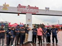 Rusman (lima, kanan) bersama wakil penaja Rasaku dan pegawai DEFM di hadapan pintu gerbang Bazar Ramadan Stadium Shah Alam yang alami perubahan lebih sistematik.