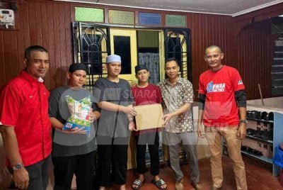 Mohd Radzmin (dua dari kanan) menyampaikan sumbangan kepada Muhammad Fadzlin (tiga dari kiri) sekeluarga menerusi program Singgah Sahur. 