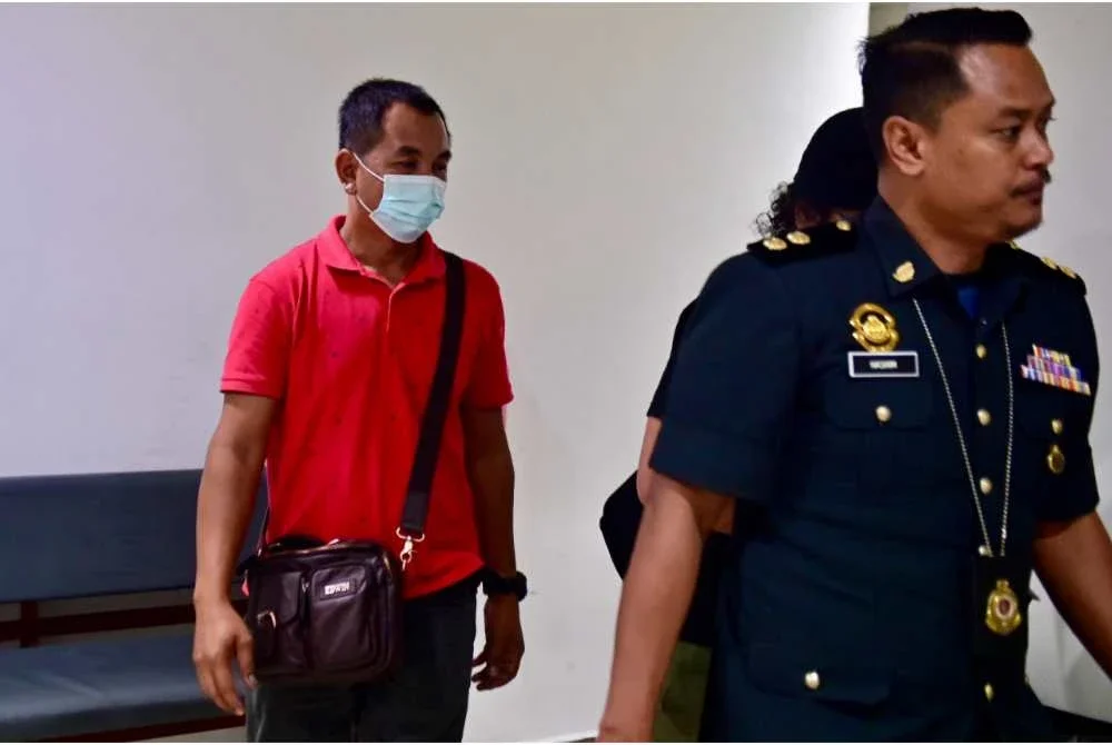 Hasdi (kiri) ketika dihadapkan di Mahkamah Sesyen di Kuala Terengganu pada Ahad.