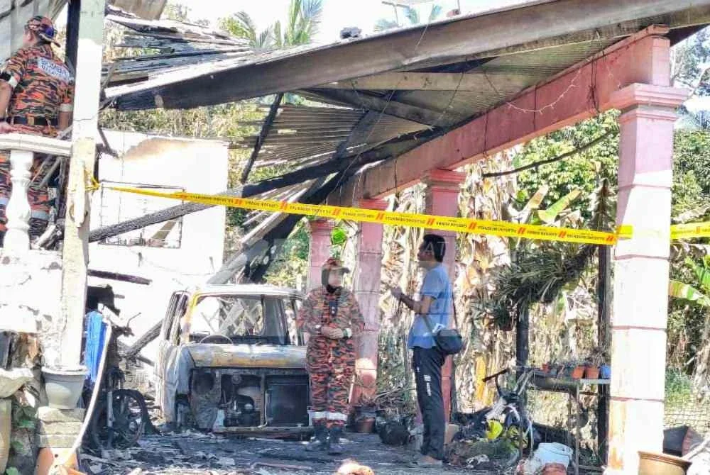 Suami kepada Nor Haida memberitahu sesuatu kepada anggota forensik bomba yang sedang menjalankan siasatan berhubung punca kebakaran tersebut. Foto Sinar Harian.