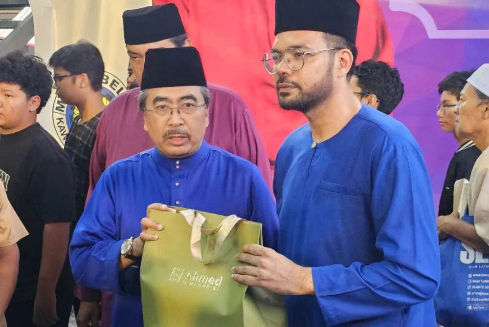Khairul Rizam (kanan) menyampaikan cenderahati kepada Johari (kiri) selepas menyempurnakan program Sentuhan Ramadan di Kampung Bahru, Kuala Lumpur.