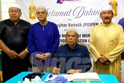 Saifuddin Nasution (duduk) menandatangani buku lawatan sempena semasa hadir ke Majlis Bersahur sempena Program Penerapan Nilai-Nilai Murni di PUSPEN Bachok pada Ahad.